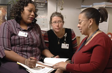 three women talking over a booklet
